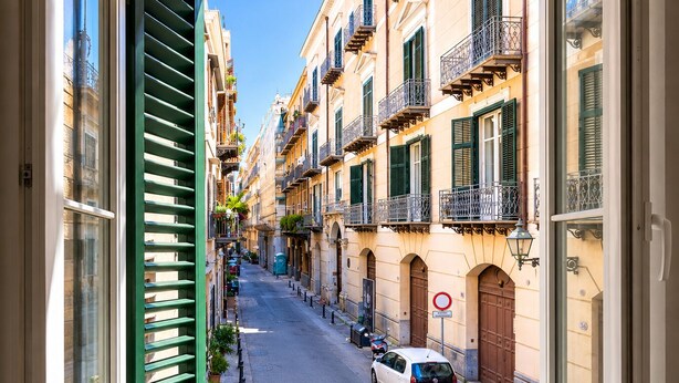 A narrow street with parked cars, traditional architecture, and a view through an open window. - Butera Apartments Luxury (Palermo)
