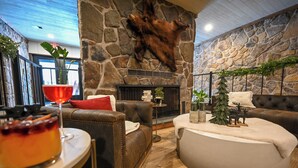 A cozy living room with a stone fireplace, leather sofas, and a round coffee table. - Cove Creek Lodge: 103 Poolside Executive King Suite (Oakland)