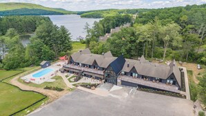A lodge with a swimming pool, outdoor seating, and a view of a lake. - Cove Creek Lodge: 103 Poolside Executive King Suite (Oakland)
