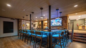 A bar area with wooden flooring, bar stools, and pendant lighting. - Cove Creek Lodge: 103 Poolside Executive King Suite (Oakland)