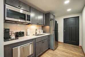 Una cocina moderna con electrodomésticos de acero inoxidable, microondas integrado y cafetera.