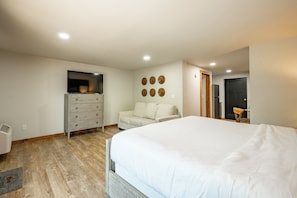 A bedroom with a large bed, a dresser, a TV, and a wall-mounted circular decoration.
