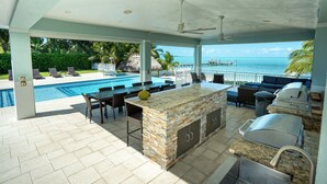 Una cocina al aire libre con piscina y vistas al océano.