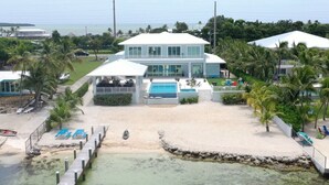 Una propiedad frente a la playa con piscina, palmeras y vista al océano.