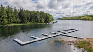 Un lago tranquilo con un muelle que se adentra en el agua, rodeado de un bosque denso.