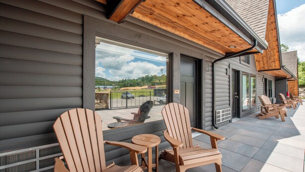 An outdoor seating area with Adirondack chairs and a small table, overlooking a scenic landscape.