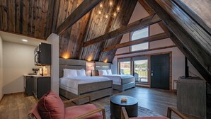 Une chambre spacieuse aménagée en mezzanine, avec un grand lit, un bureau et une vue sur l’extérieur.