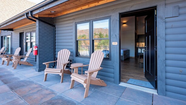 A building with a covered patio area, wooden chairs, and a fire extinguisher.