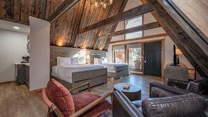 A spacious loft bedroom with a large bed, a sofa, and a chair. - Cove Creek Lodge: 217 Lakeside Double Queen Fireplace Room (Oakland)