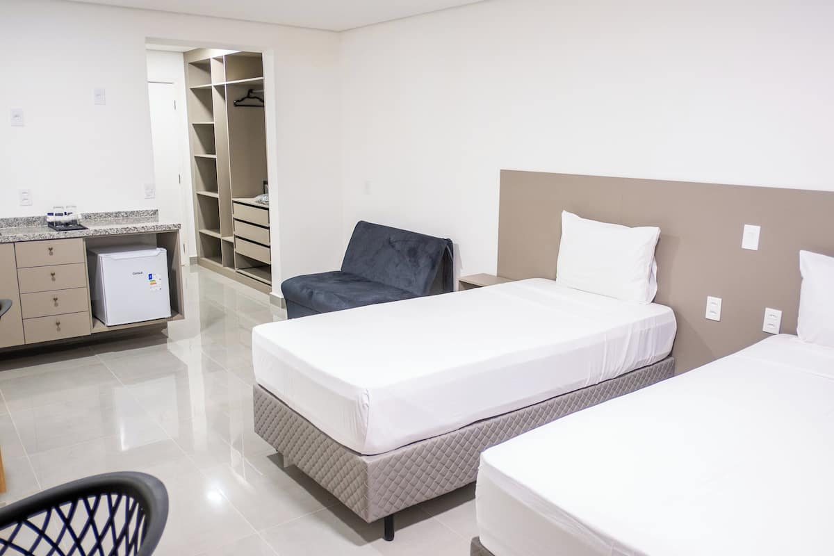 Une chambre d’hôtel comprenant un lit, une chaise, un bureau avec un ordinateur et une armoire.