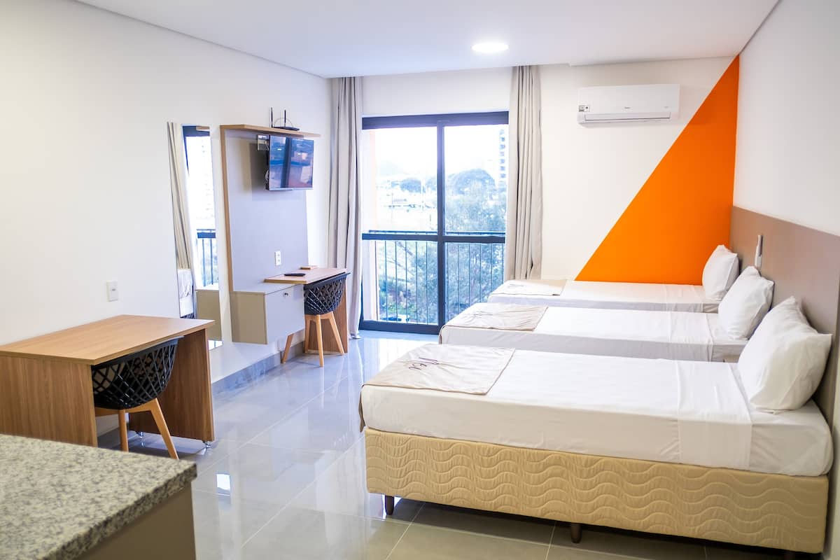 Une chambre d’hôtel avec deux lits, un bureau, une chaise et un téléviseur.