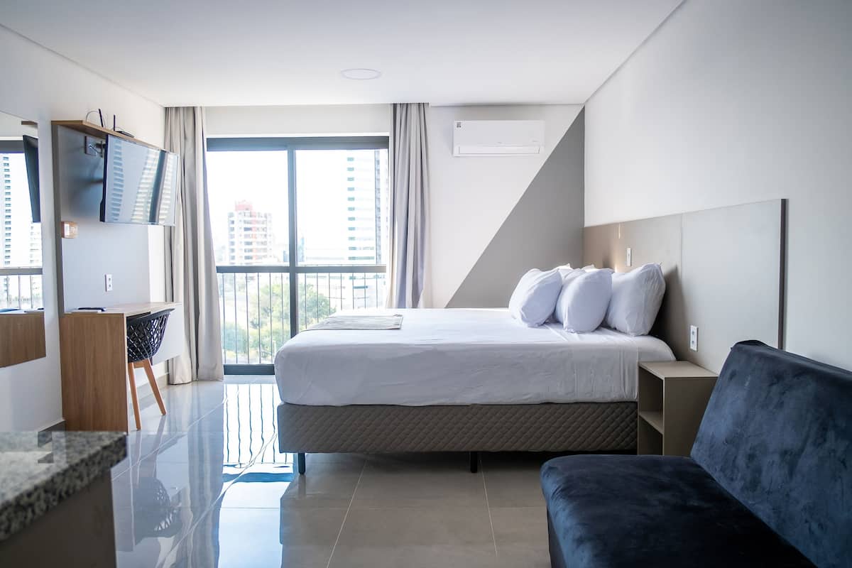 Une chambre d’hôtel moderne dotée d’un grand lit, d’une télévision à écran plat, d’un bureau et offrant une vue sur la ville.