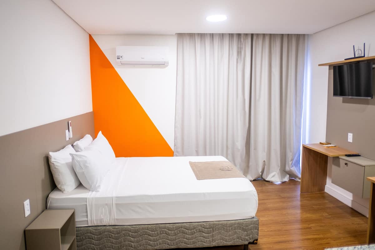 Une chambre d’hôtel moderne équipée d’un lit, d’un bureau, d’un climatiseur et d’une télévision.