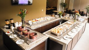 Un buffet proposant une variété de plats, avec un écran de télévision en arrière-plan.