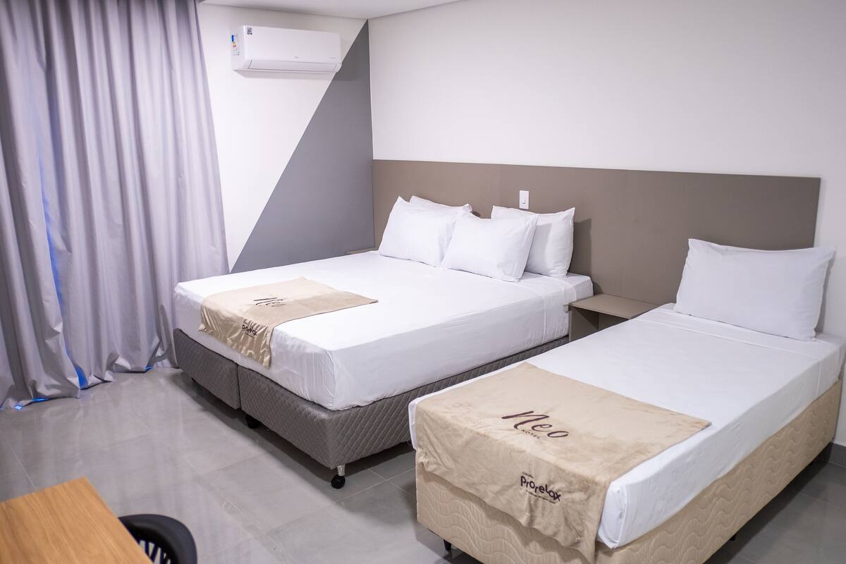 Une chambre d’hôtel avec deux lits, un bureau et une chaise.