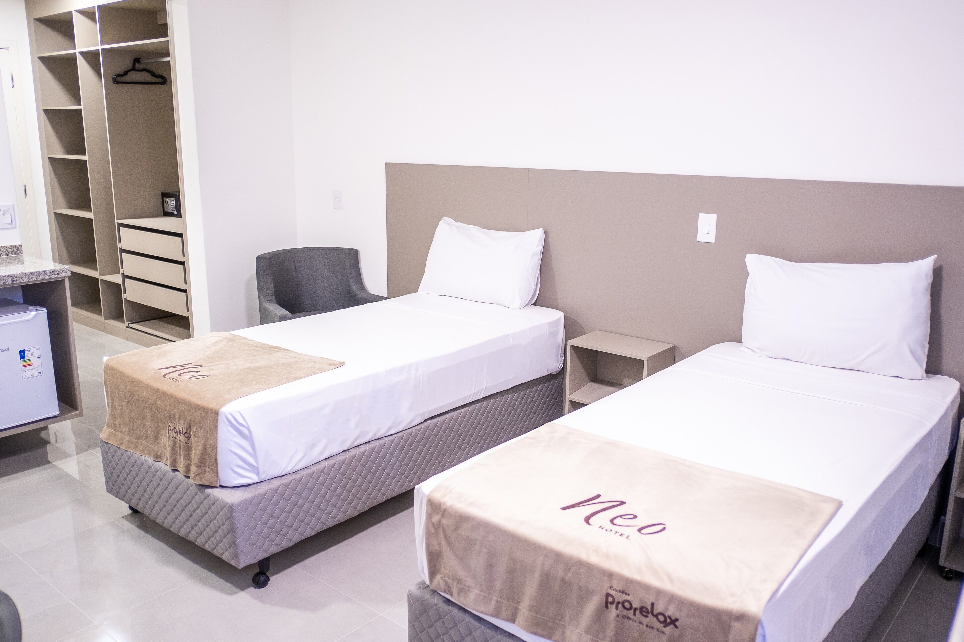 A hotel room with two beds, a desk, a chair, and a walk-in closet.