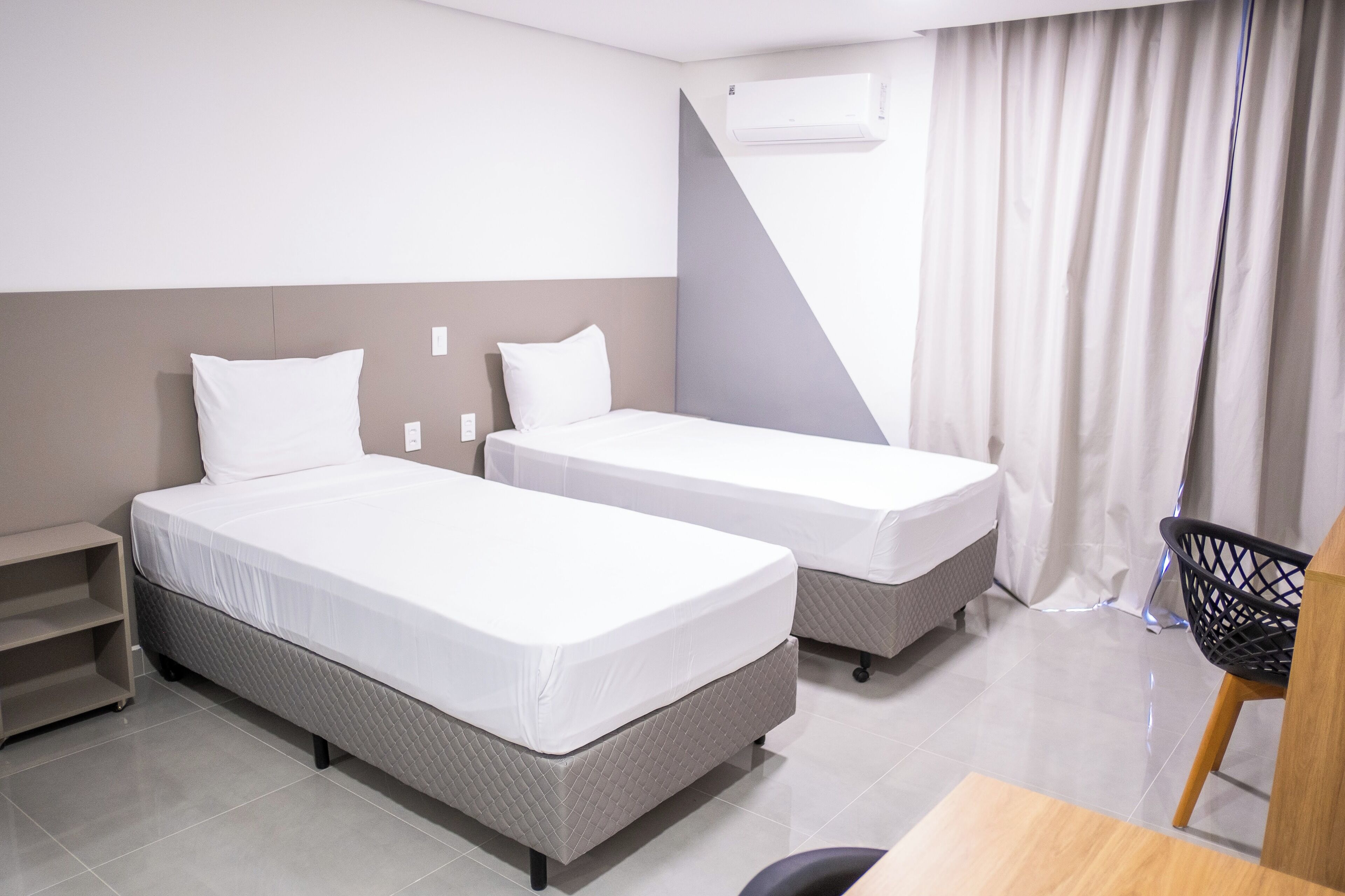 Habitación de hotel con dos camas, un escritorio y una silla.