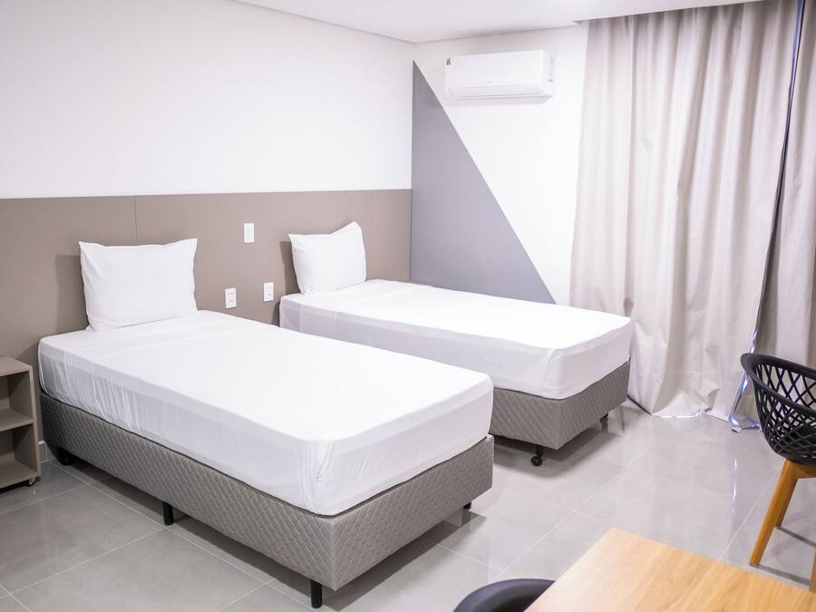 Habitación de hotel con dos camas, un escritorio y una silla.