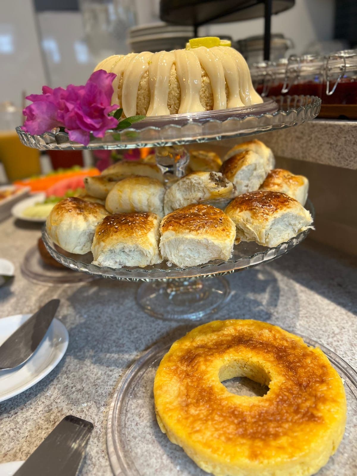 A dessert display with a cake, pastries, and a donut on a glass stand.