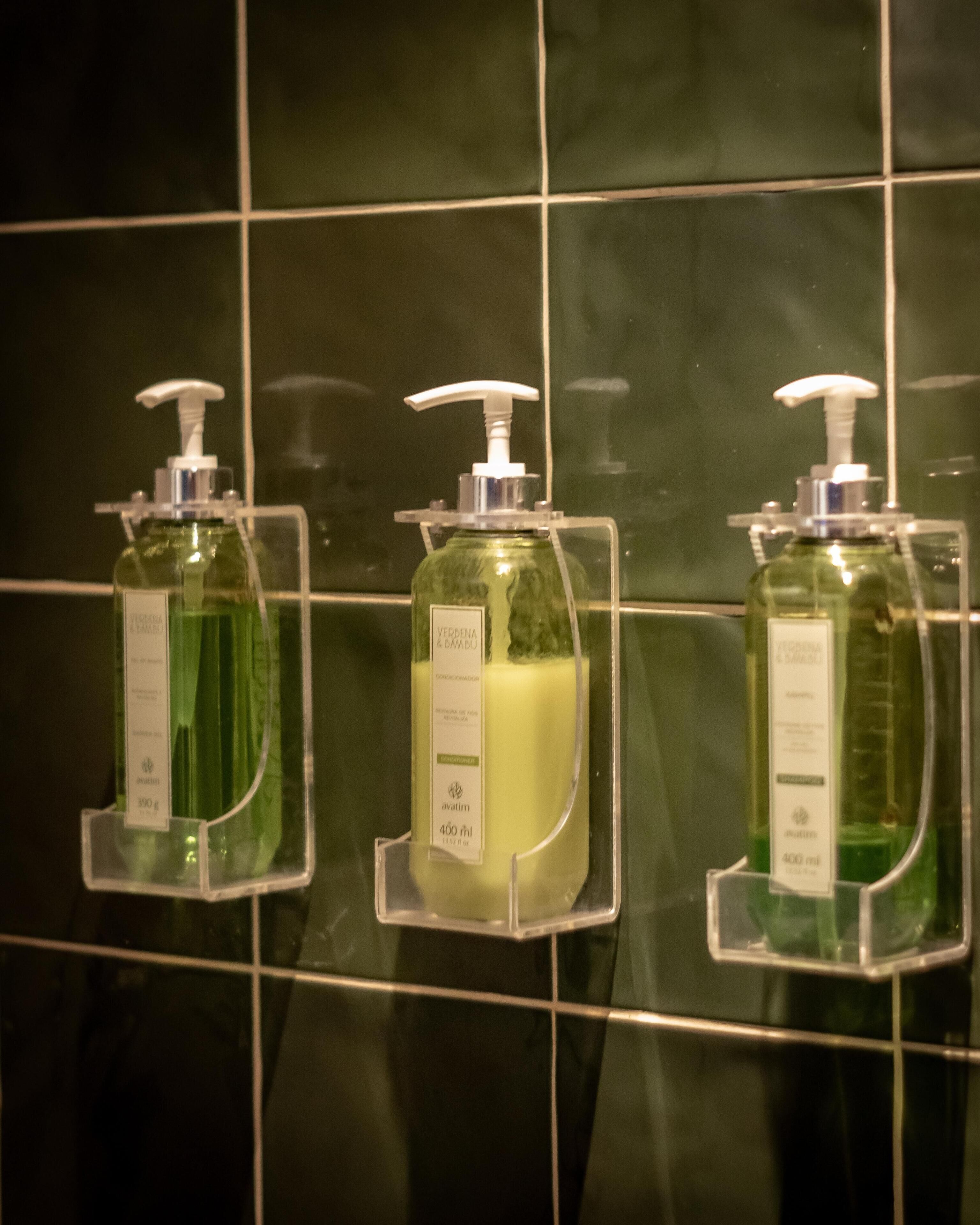 Three hand sanitizer dispensers mounted on a tiled wall.