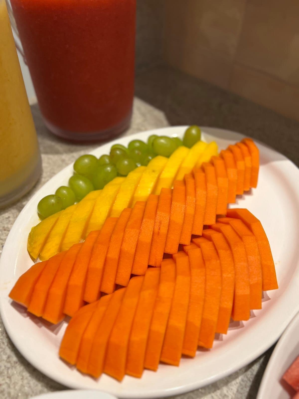 A plate with sliced fruits and a glass of red liquid.