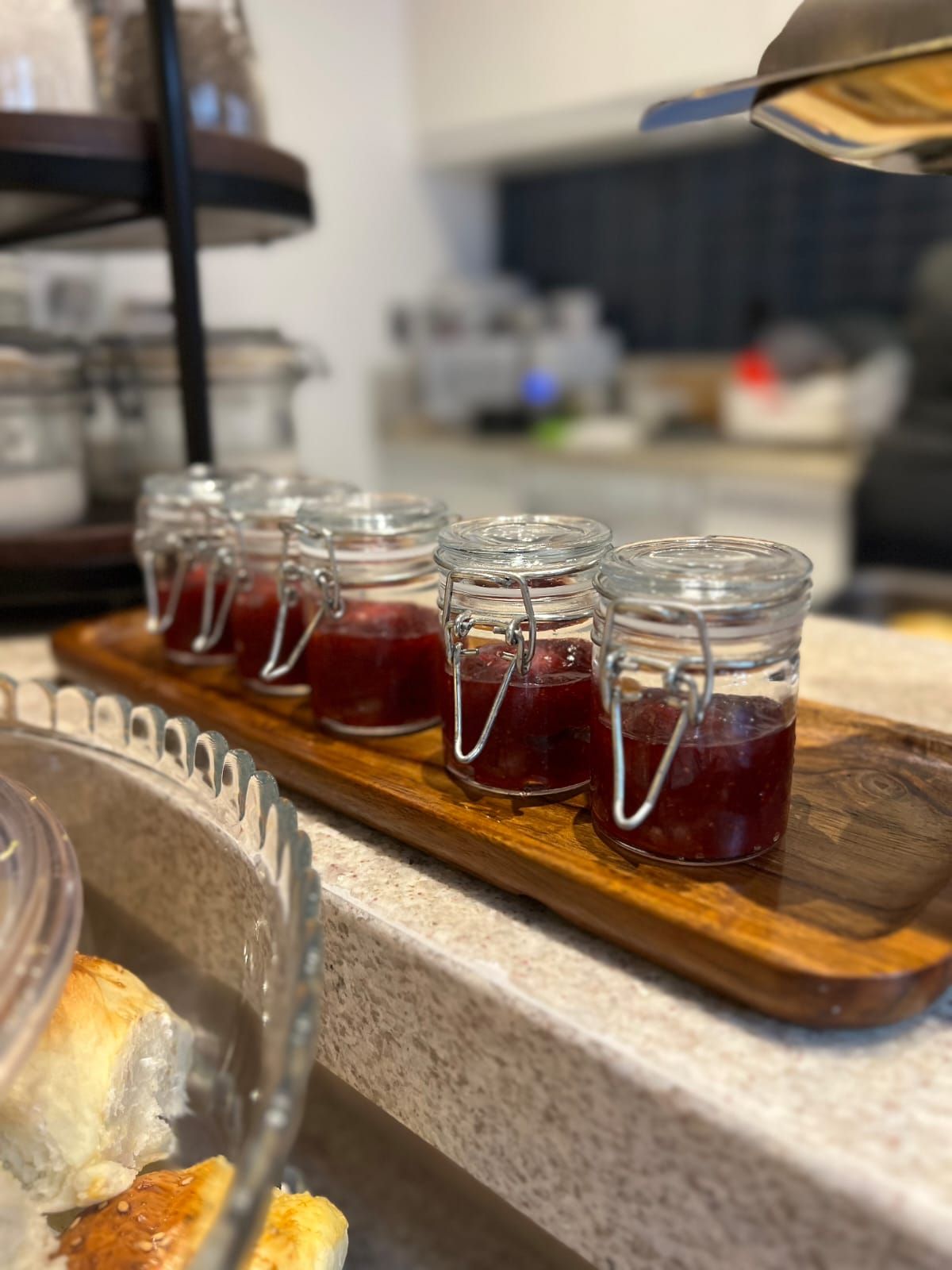 A tray with several glass jars containing a red substance, possibly jam, on a kitchen counter.