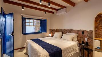 A bedroom with a large bed, a stone accent wall, a window with shutters, and a ceiling fan.