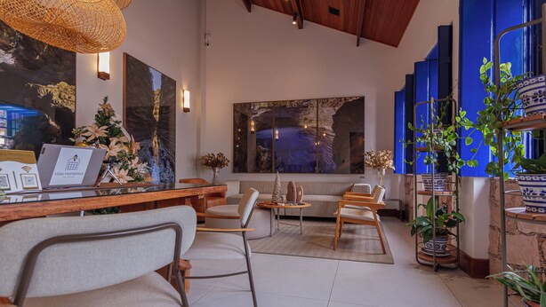 Un interior moderno con un mostrador de recepción de madera, una zona de estar con sofás y sillones, y un ventanal con vistas.