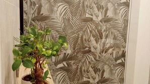 A bathroom with a potted plant on a wooden surface, a white sink, and a shower area with a leaf-patterned shower curtain. - Home Sicily Pachino r1 (Pachino)