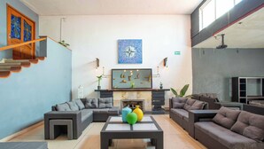 A modern living room with a sectional sofa, a coffee table, and a fireplace. - La Paz & Love Hostel (Guadalajara)