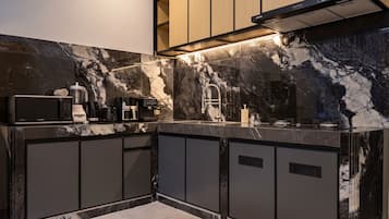 A modern kitchen with a marble backsplash, built-in appliances, and a stainless steel range hood.