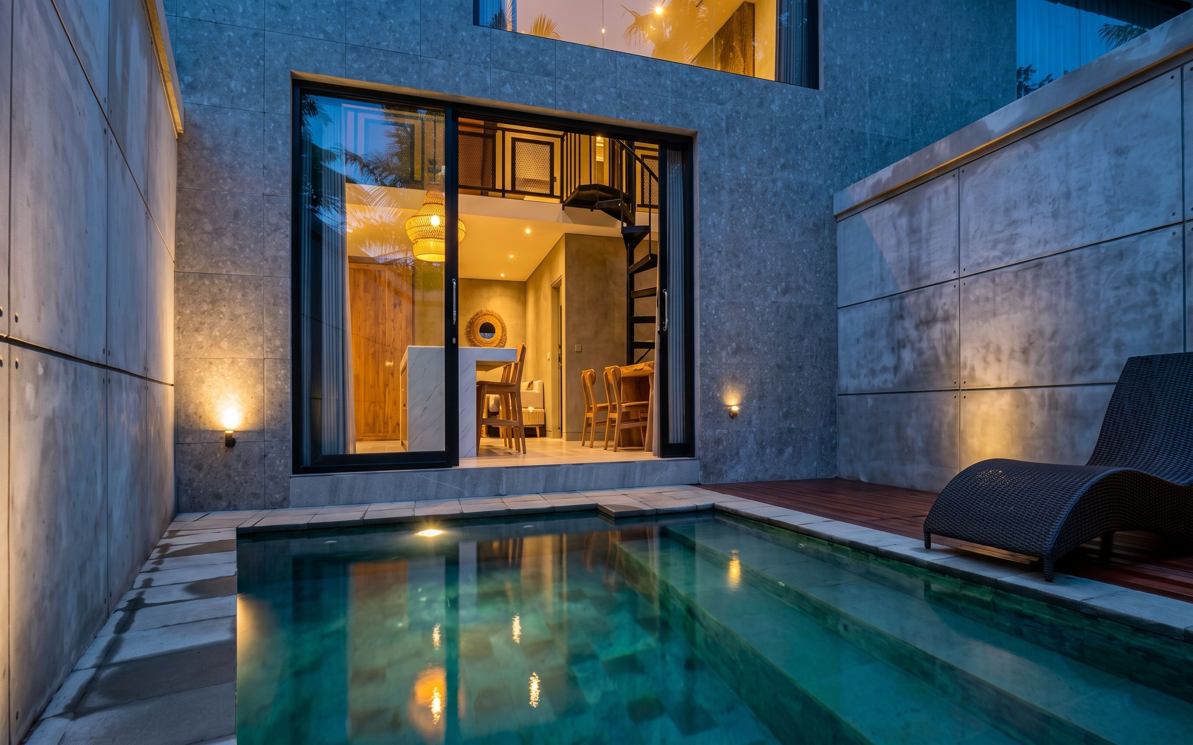 A modern outdoor pool area with a clear pool, a wooden deck, and a seating area with a chair.