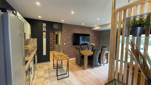 Een moderne keuken met een ingebouwde koelkast, een eethoek met een bakstenen muur en een aan de muur bevestigde televisie.