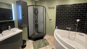Een moderne badkamer met een douche met glazen wand, een vrijstaand bad en een wastafel met spiegel.