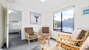 A room with wicker furniture, a glass table, and a large window with a view of the outdoors.