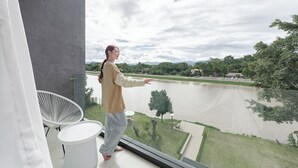Un balcon donnant sur une rivière et un paysage verdoyant.