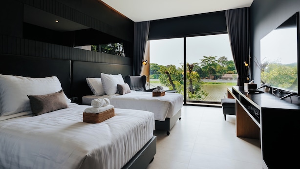 Une chambre d’hôtel moderne, dotée de deux lits, d’un bureau et d’une grande fenêtre donnant sur l’extérieur.