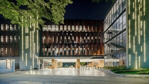 Un bâtiment moderne doté d’une grande entrée, de bandes lumineuses verticales et d’un espace abrité comprenant des sièges et des supports à vélos.