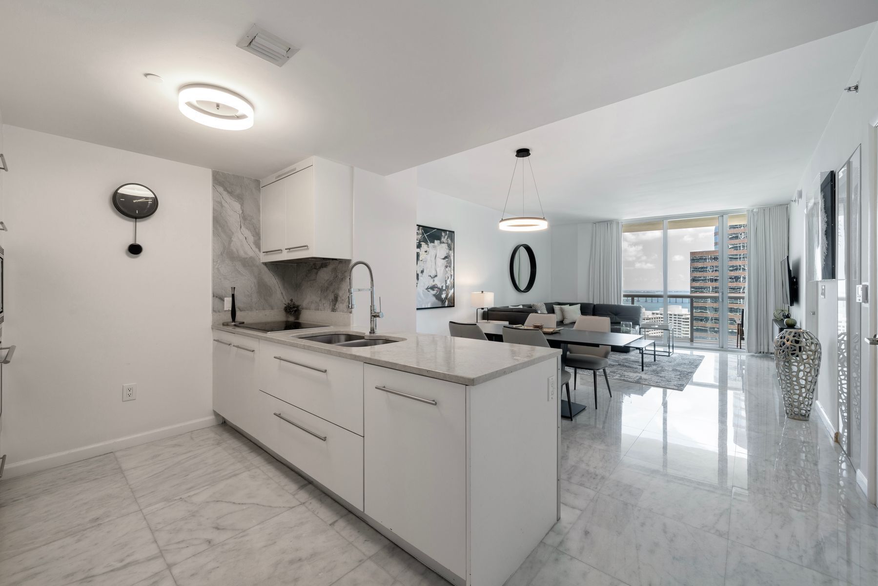 Une cuisine moderne avec des meubles blancs, un pare-feu en marbre et un îlot central.