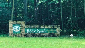 Un letrero de piedra con la inscripción "Blue Knob All Seasons Resort" rodeado de follaje.