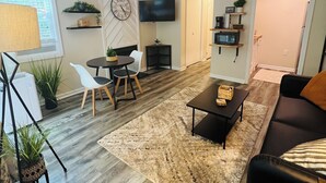 Una sala moderna con sofá, mesa de centro y televisor montado en la pared.
