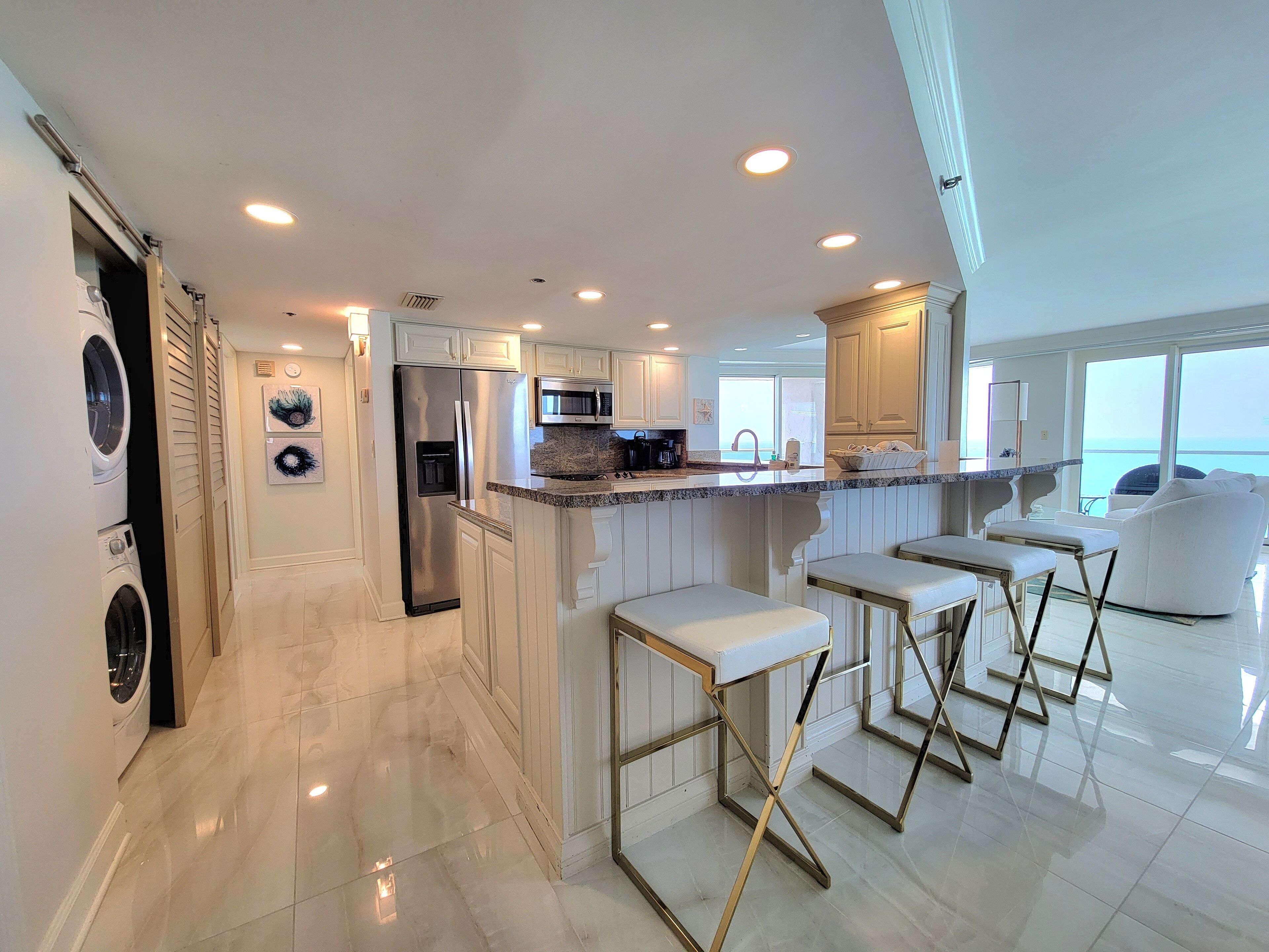 Una cocina moderna con una isla central, electrodomésticos de acero inoxidable y vista al mar.