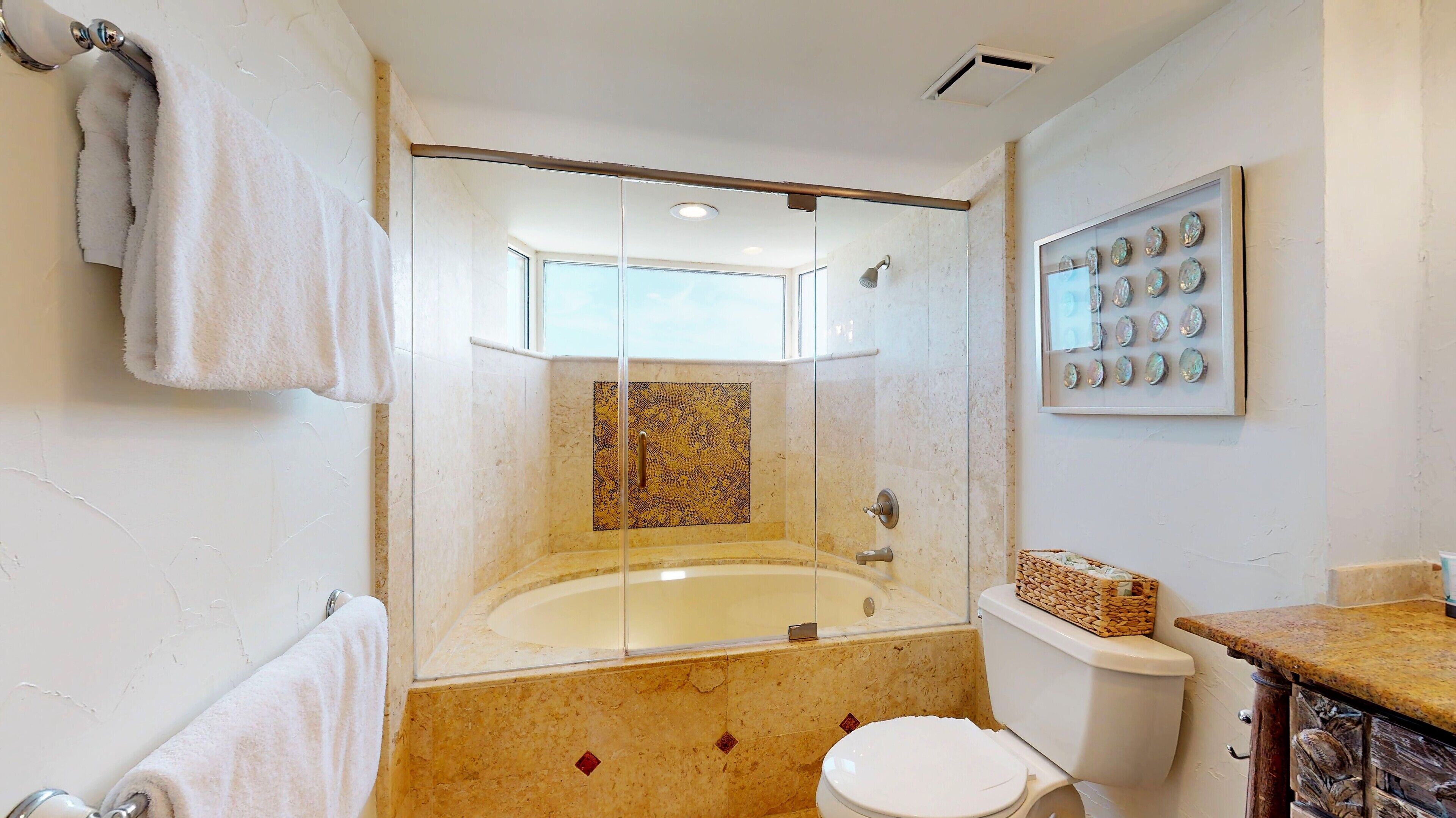 A bathroom with a glass-enclosed shower, a toilet, and a sink.