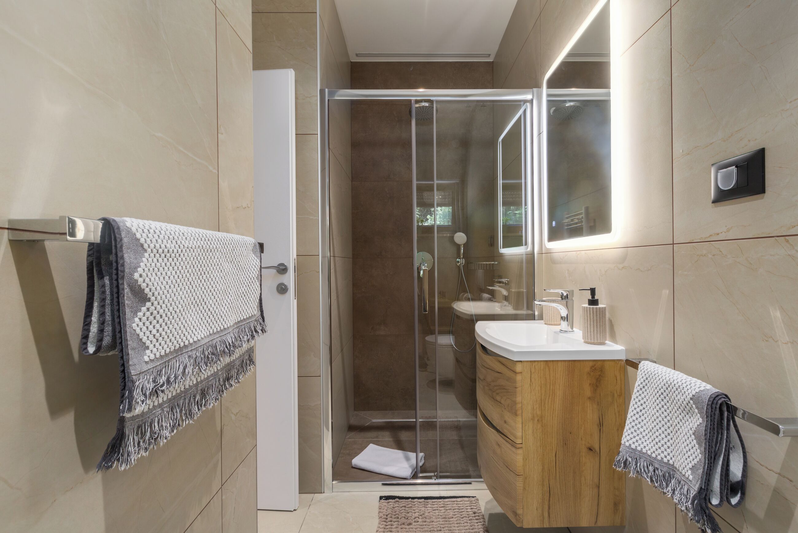 A modern bathroom with a glass-enclosed shower, a wooden vanity, and a large mirror.