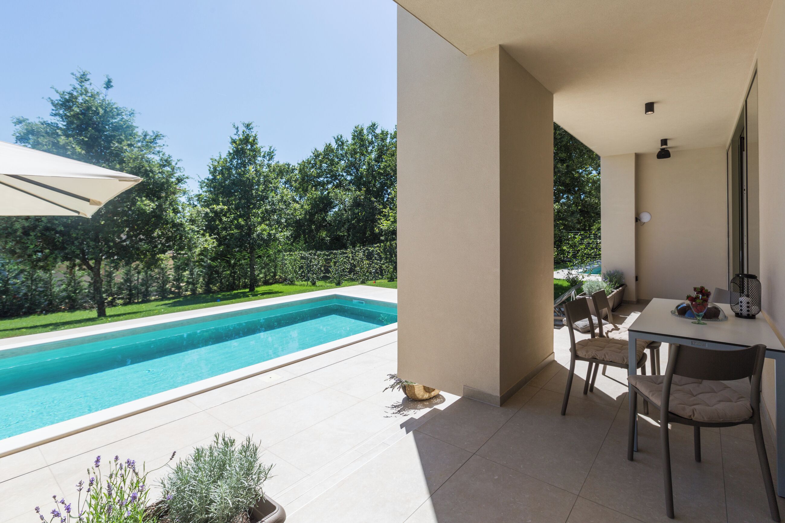 En moderne udendørs terrasse med pool, spisebord og stole.