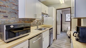 A compact kitchen with white cabinets, a built-in oven, and a dishwasher.