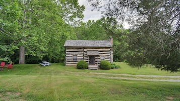 Escape to a serene cabin surrounded by lush greenery and a well-manicured lawn, perfect for relaxation and outdoor activities.
