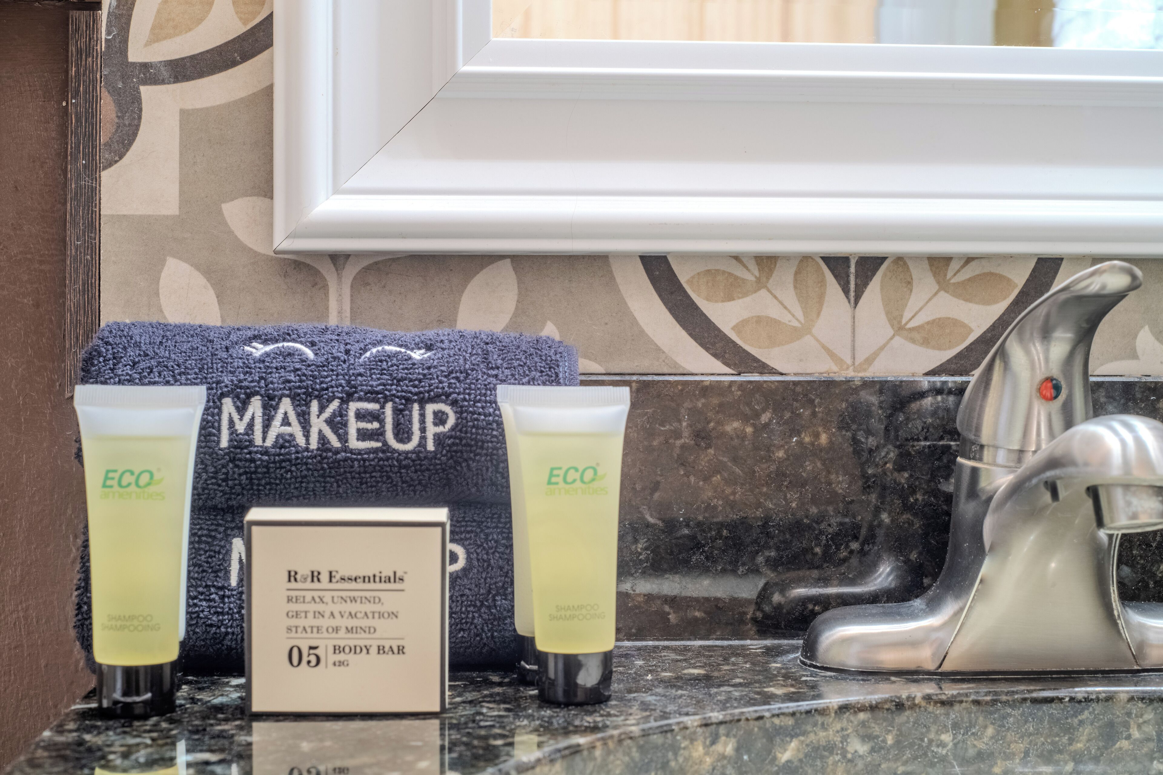 Un meuble-lavabo de salle de bain avec une serviette, deux flacons de shampoing de la marque ECO, un savon et un robinet.