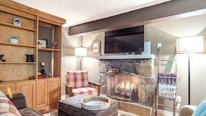 Una sala de estar acogedora con chimenea de piedra, estanterías de madera y asientos cómodos.