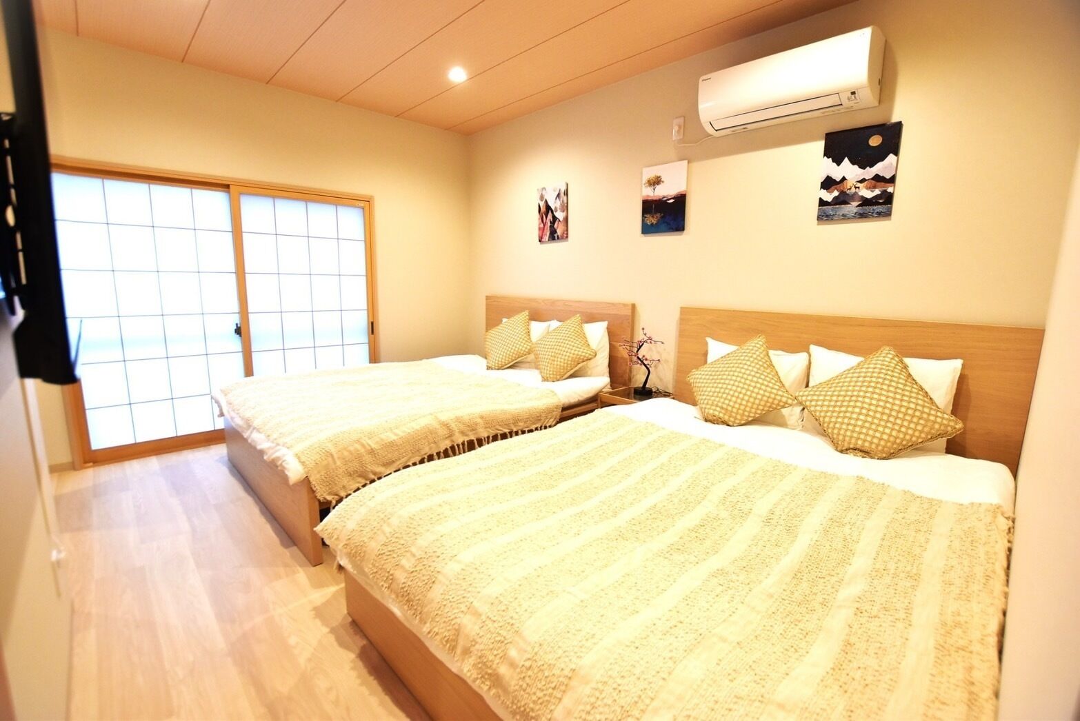 A hotel room with two beds, a sliding door, and a wall-mounted air conditioner.